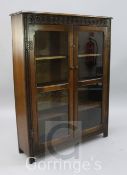 An oak two door glazed bookcase, with guilloche carved frieze, width 3ft 1in.