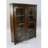 An oak two door glazed bookcase, with guilloche carved frieze, width 3ft 1in.