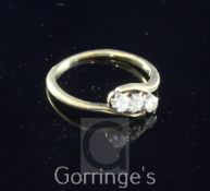 A 18ct gold and three stone diamond ring, the three round cut diamonds in a twist setting, size M.