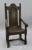 An early 18th century oak wood seat elbow chair, with an arched topped fielded panelled back