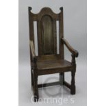 An early 18th century oak wood seat elbow chair, with an arched topped fielded panelled back