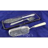 A cased pair of Victorian plated fish servers and an ivory handled silver plated crumb scoop.