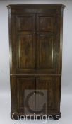 A late 18th century oak standing corner cupboard, fitted with two pairs of fielded panelled doors,