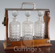 An Edwardian plated mounted oak tantalus, fitted three cylindrical hob nail cut glass spirit