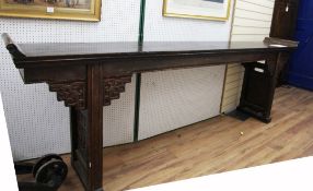 A large Chinese dark stained softwood altar table, the ends carved with stylised scrollwork