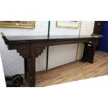 A large Chinese dark stained softwood altar table, the ends carved with stylised scrollwork