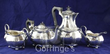 An Edwardian four piece silver tea set, of oval bombe shape, with fluted angle and ebonised handles,