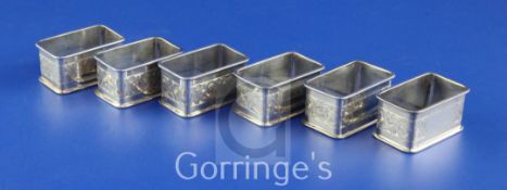 A matched set of six George V silver rectangular napkin rings, with engraved foliate decoration,