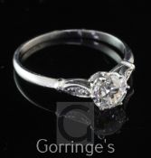 A platinum and single stone diamond ring with diamond set shoulders, the central stone weighing