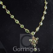 An Edwardian 9ct gold and peridot pendant necklace, set with twenty six round or oval cut stones,