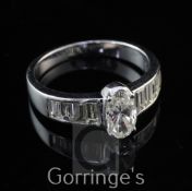 A 14ct white gold and diamond dress ring, set with central oval cut diamond and graduated baguette