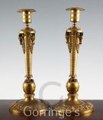 A pair of 19th century French Empire style ormolu candlesticks, with stylised goats head motifs,