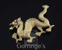 A high carat gold brooch modelled as an Eastern dragon, with cabochon set eye and gilt metal pin,