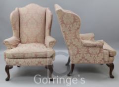 A pair of George III style mahogany wing armchairs, with pale pink damask upholstery, on foliate