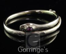 An 18ct gold and cabochon ruby set serpent hinged bangle, gross weight 17 grams.