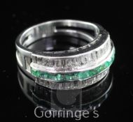 A white gold channel set emerald and diamond ring, with central band of rectangular cut emeralds,