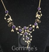 An Edwardian gold, amethyst and seed pearl set drop pendant necklace, of open work scrolling design,