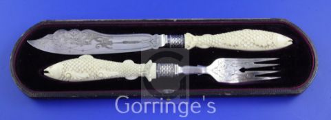 A cased small pair of Victorian carved ivory handled and silver fish servers, each handle modelled