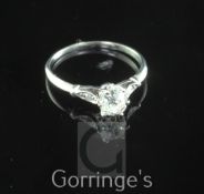 A platinum and single stone diamond ring, with diamond set shoulders, the central cushion cut