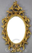 A Chippendale style giltwood wall mirror, with oval plate and foliate surround, W.1ft 5in. H.2ft