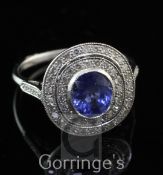 An 18ct white gold, sapphire and diamond cluster target ring, the central oval cut sapphire weighing