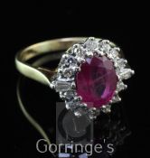 An 18ct gold, ruby and diamond oval cluster ring, the oval cut ruby weighing approximately 1.50-2.