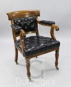 A Victorian oak Holland & Son elbow chair, with buttoned black leather upholstery and brass castors,