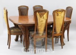 A Louis Majorelle 'Chicoree' pattern oak dining table and six chairs, the table with moulded rounded
