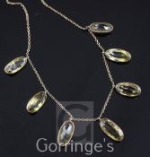 An early 20th century 9ct gold and citrine drop necklace, set with seven oval cut stones, (clasp a.