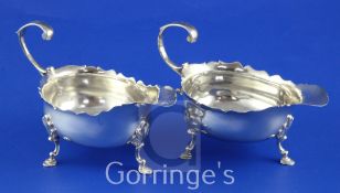 A pair of late George II silver sauce/cream boats, with flying scroll handles and shaped cut rims,