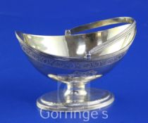 A George III silver boat shaped pedestal sugar basket, with engraved armorials and reeded handle and