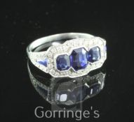 A white gold three stone sapphire and diamond cluster ring, with sapphire and diamond set shoulders,