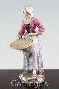 A Meissen figure of a female street vendor, 19th century, holding a coiled rope or mat, underglaze