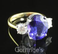 An 18ct gold, tanzanite and diamond three stone ring, the central oval cut tanzanite flanked by