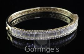 An 18ct gold and diamond hinged bangle, with seventy channel set baguette cut diamonds and brilliant