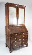 A George I burr walnut bureau bookcase, with moulded cornice and two bevelled mirrors doors