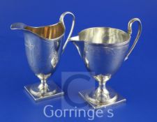 A George III silver vase form cream jug and a similar helmet shaped cream jug both with engraved