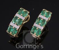 A modern pair of 18ct gold, emerald and diamond cluster earrings, of convex form, set with three