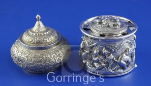 An early 20th century Indian silver circular inkwell, continuously embossed with deities, the top