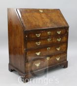 A George I walnut bureau, the fall enclosing pigeon holes, drawers and central cupboard over four