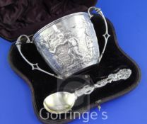 A cased Victorian repousse silver christening porringer and spoon, decorated with continuous scene