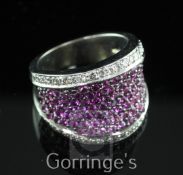 A modern white gold and pave set ruby dress ring with brilliant cut diamond set borders, size M.