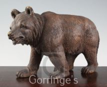 An early 20th century Black Forest carved wood bear, with glass inset eyes, length 12in.