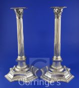 A pair of George V silver corinthian column candlesticks, with tapering stems, on shaped octagonal
