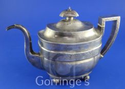 A George III silver teapot, of rounded rectangular form, with engraved floral band, on ball feet,
