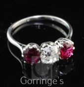 An early 20th century platinum and three stone ruby and diamond ring, the cushion cut diamond