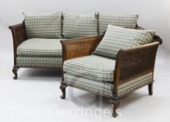 A 1930's mahogany double caned three piece bergere suite, with blue chequer upholstery, on scallop