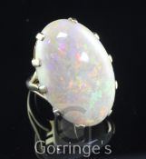 A large 9ct gold and opal dress ring, the claw set oval stone measuring 30mm by 22mm by 5mm, size