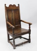 A 17th century oak armchair, with panelled back and solid seat, H.3ft 8in.