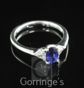 A modern 18ct white gold, sapphire and diamond ring, with central oval cut blue sapphire flanked